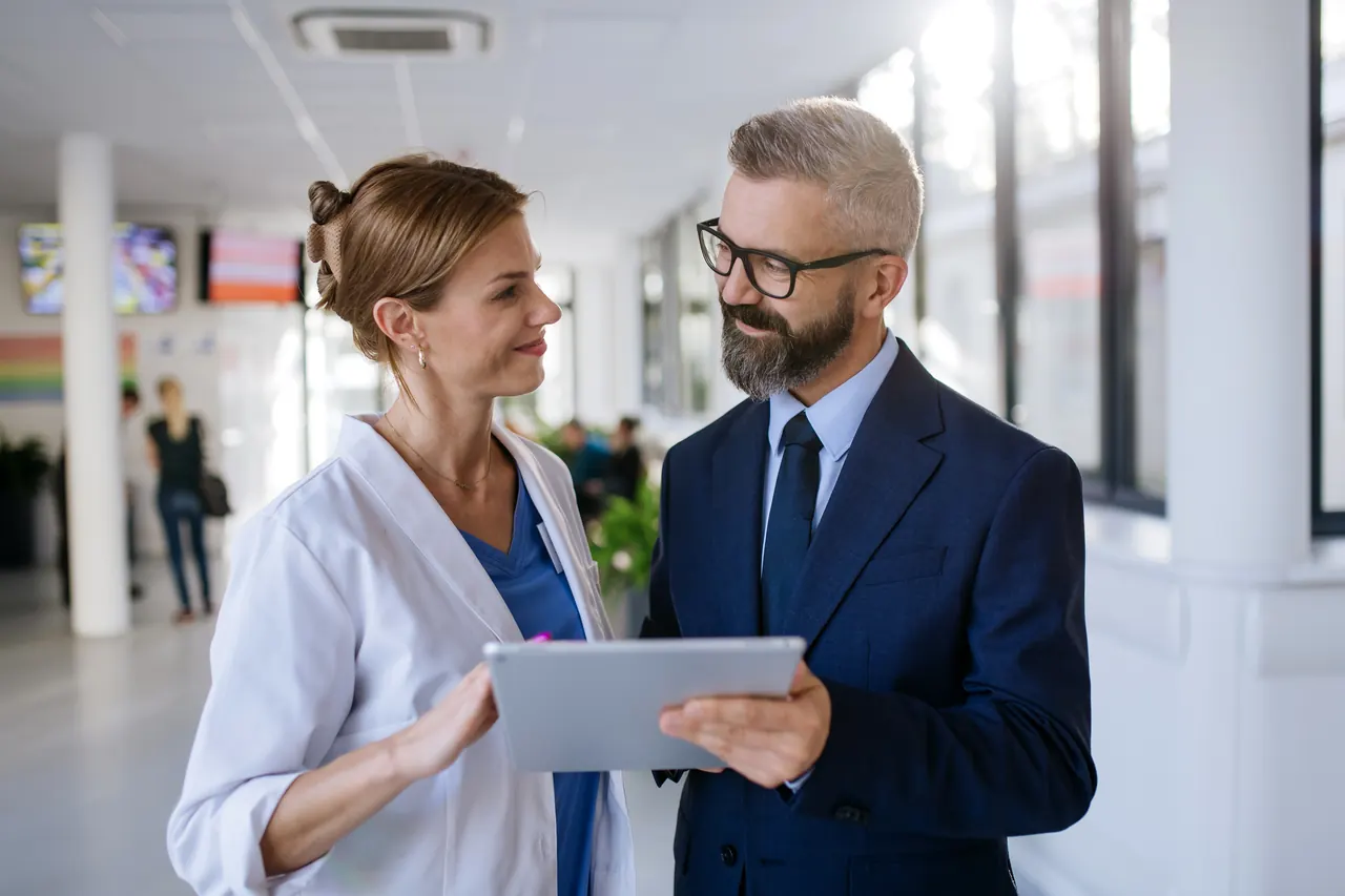 Medical equipment sales rep reviewing an account with a hospital clinician on a tablet